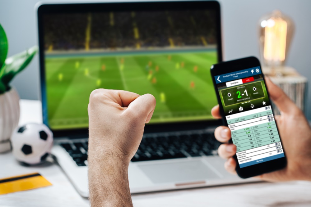 Voetbal kijken op een laptop met een wedstrijdscherm op de telefoon